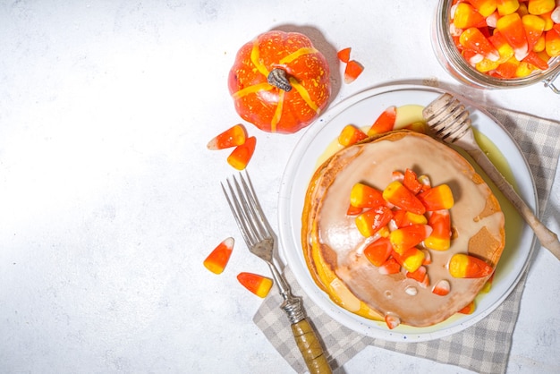 Homemade candy corn pancakes. Stack of yellow and orange pancakes with sweet sauce and traditional Halloween candy cord candies