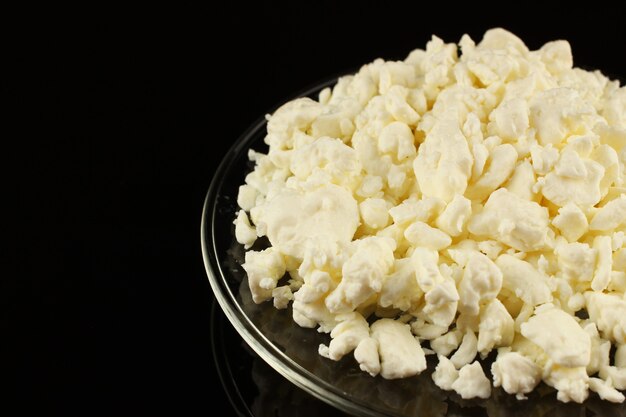 Homemade cheese on a transparent plate on a black surface place for text cope space