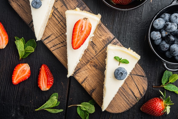 Homemade cheesecake with fresh berries, on black wooden table