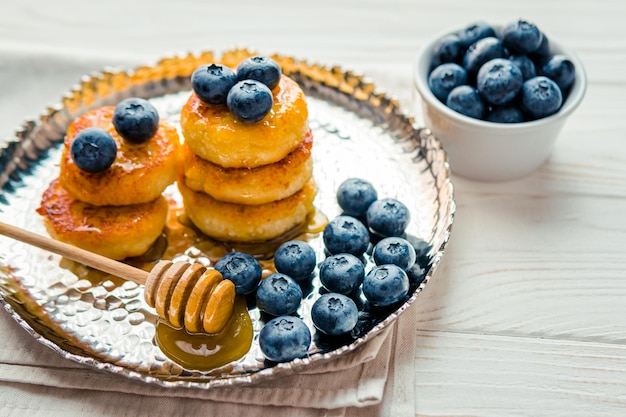 Homemade cheesecake with freshly picked juicy blueberries in the plate on wooden background close up