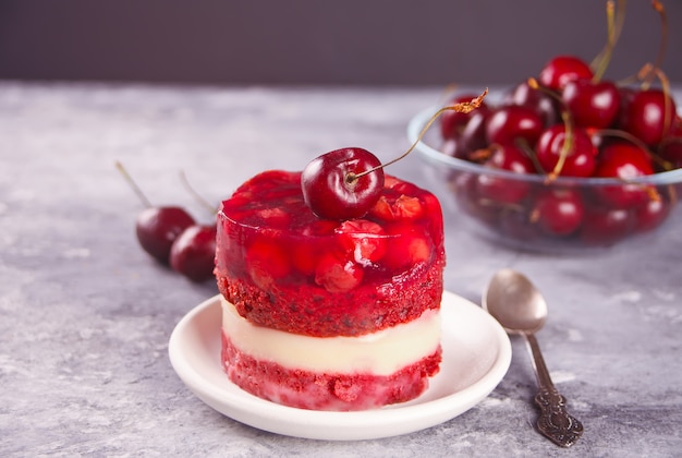 Homemade cherry cake with vanilla cream and cherry jelly on gray 