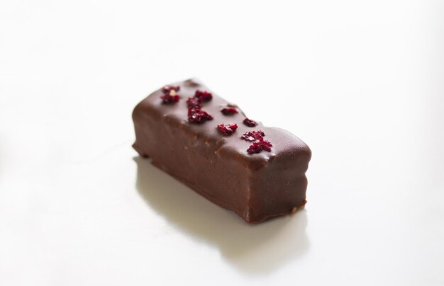 Photo homemade chocolate bar with dry piece of cherry on top on the white background