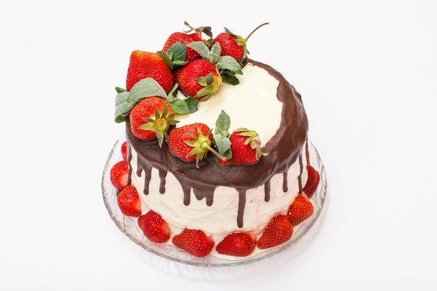 Homemade chocolate cake decorated with fresh strawberries on glass plate and on white background