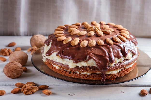 Homemade chocolate cake with milk cream and almonds on white wood