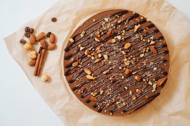 Homemade chocolate cake with nuts on parchment paper Food delivery Homemade baking Delicious tart with chocolate and nuts on the white table Side view