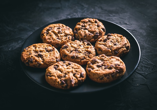 homemade chocolate chip cookies on a black plate on a dark table