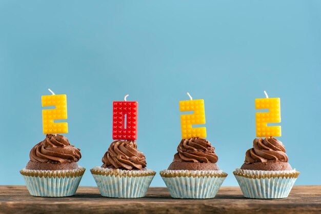 Homemade chocolate cupcakes with 2022 number colorful candle on blue background. Happy New Year theme.