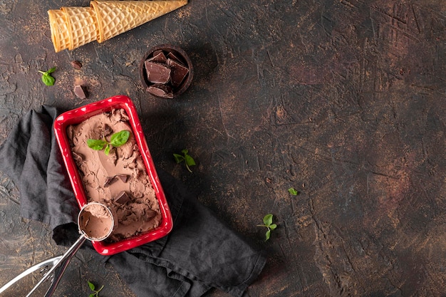 Homemade chocolate ice cream in a bowl with chocolate and mint on the dark background top view copy