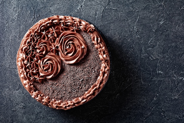 Homemade chocolate meringue Cake topped with Chocolate buttercream roses, horizontal view from above, flat lay, copy space