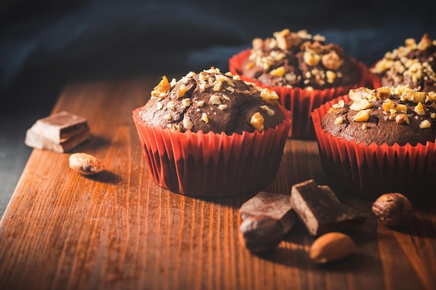 Homemade chocolate muffins or cupcakes sprinkled of nuts on a wooden board