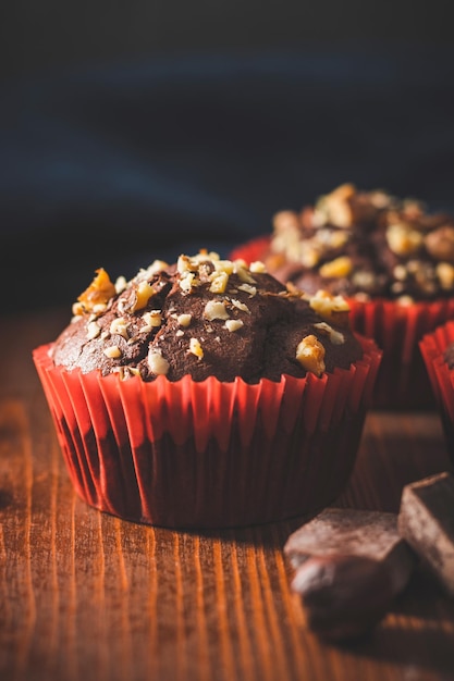 Homemade chocolate muffins or cupcakes sprinkled of nuts on a wooden board