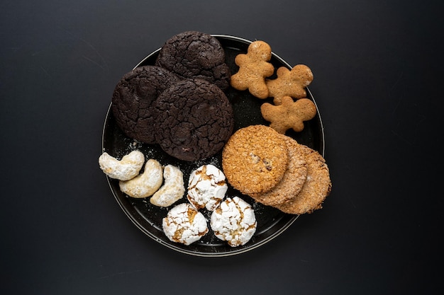 Homemade chocolate oatmeal cookies sprinkled with sugar on a black background in a black plate