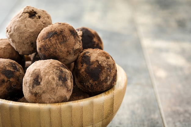 Homemade chocolate truffles in bowl on wooden table