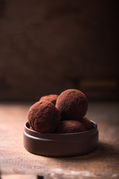 Homemade chocolate truffles  on wooden table closeup view. Tasty vegetarian candy or balls  with raw cocoa powder