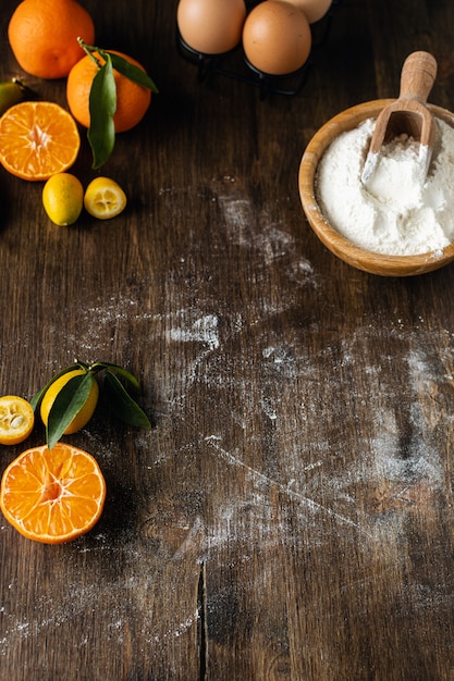 Homemade christmas baking background, wooden table with flour, eggs and tangerines