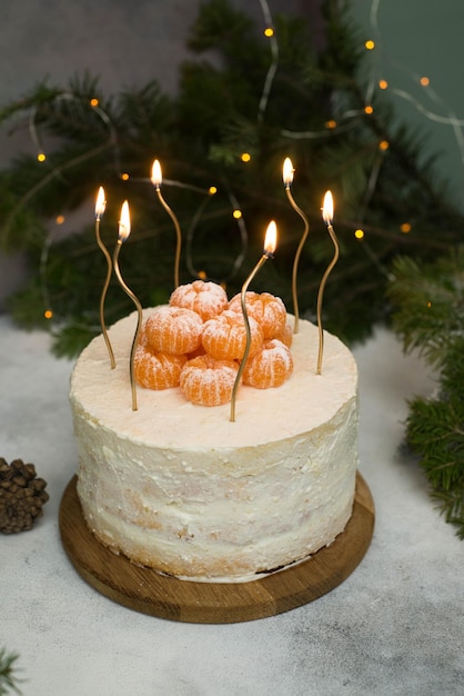 Homemade christmas cake with fir branches candles on gray background