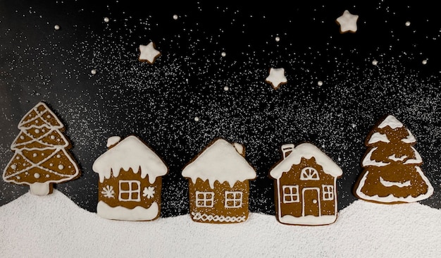 Homemade Christmas gingerbread cookies in the form of houses trees and stars laid out in the style of Christmas Eve