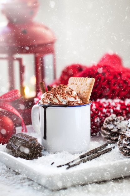 Homemade christmas hot chocolate with whipped cream, cacao and cinnamon on a plate in christmas holiday atmosphere