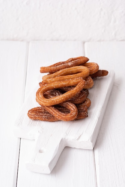 Homemade churros on a white wooden background