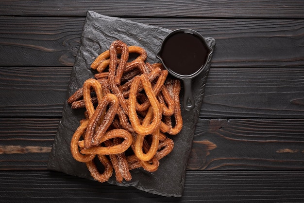 Homemade churros with chocolate on a dark wooden rustic background