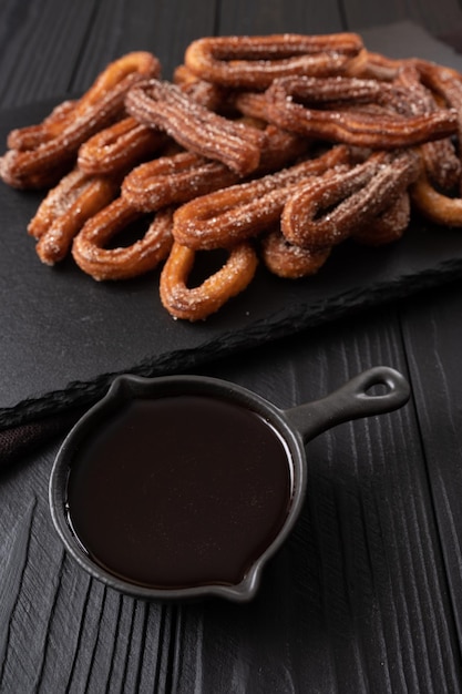 Homemade churros with chocolate on a dark wooden rustic background