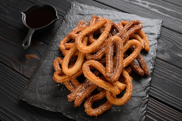 Homemade churros with chocolate on a dark wooden rustic background