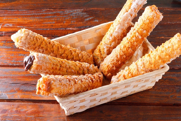 Homemade churros with multiple fillings in a basket on a rustic wooden table