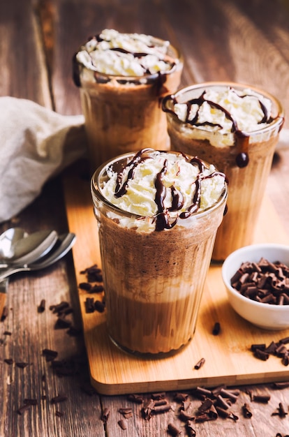 Homemade coffee coctail with whipped cream and liquid chocolate on rustic wooden background