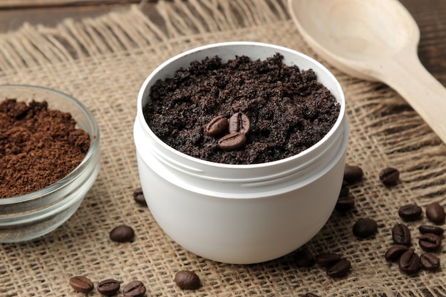 Homemade coffee scrub in a white jar for the face and body and various ingredients for making scrub.