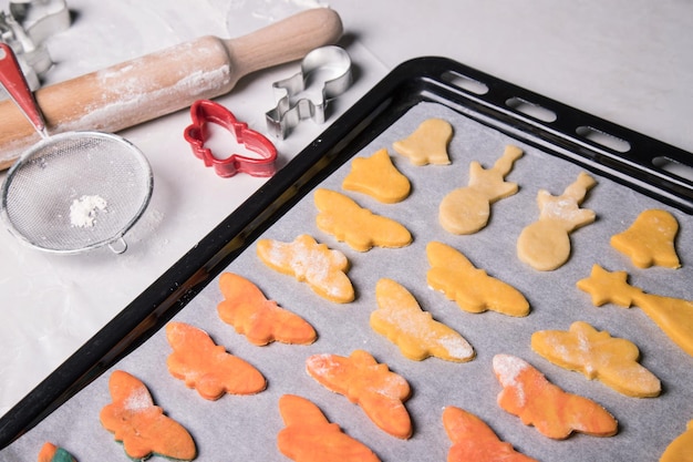 Homemade cookies in the form of butterflies bells and snowmen before baking on a baking sheet