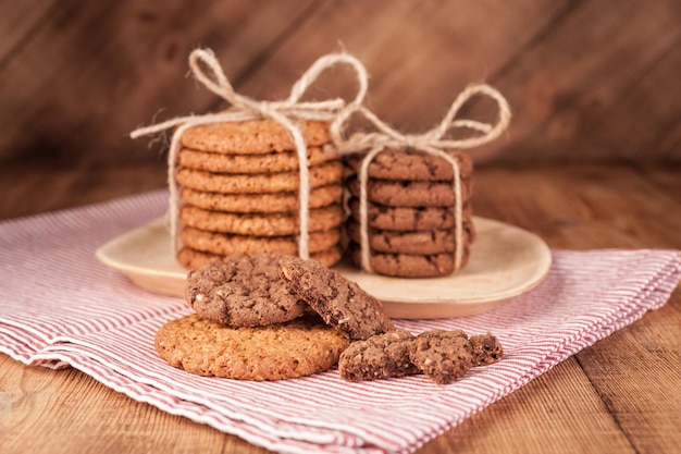 Homemade corded wholegrain cookies with oatmeal, linen and sesame seeds and traditional cookies with chocolate chips on dark rustic wooden table. Healthy vegan food concept.