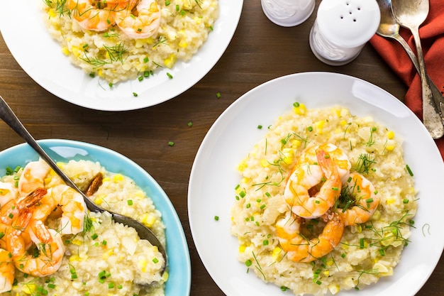 Homemade corn risotto with roasted shrimp on dining table.