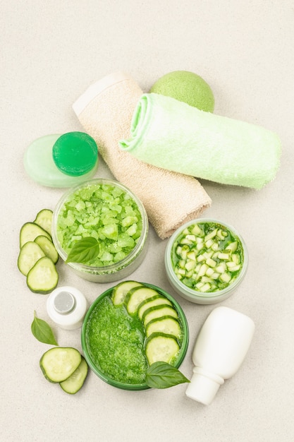 Homemade cosmetics with cucumber. Detoxification skin vegetable masks. Natural cream, sea salt, body lotion, and soap. Light stone concrete background, top view