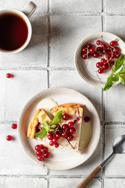 Homemade cottage cheese casserole garnished with sauce redcurrant and cup of coffee on gray tile background top view