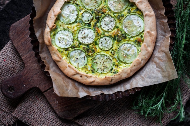 Homemade courgette and goat cheese pie on a dark rustic wooden board background