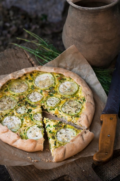 Homemade courgette and goat cheese pie on a dark rustic wooden board background