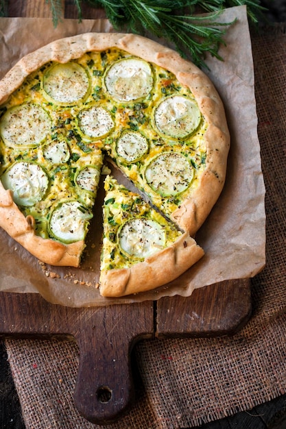 Homemade courgette and goat cheese pie on a dark rustic wooden board background