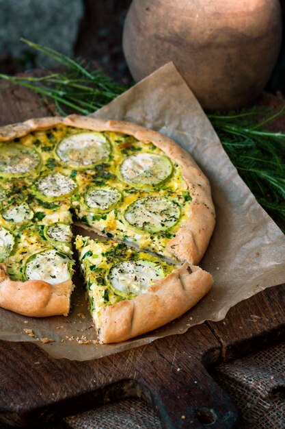 Homemade courgette and goat cheese pie on a dark rustic wooden board surface