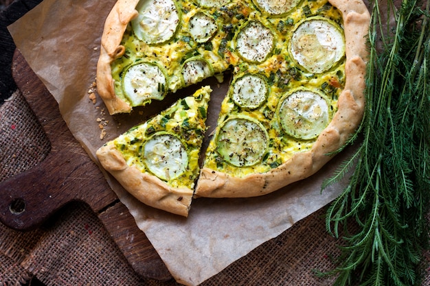 Homemade courgette and goat cheese pie on a dark rustic wooden board surface