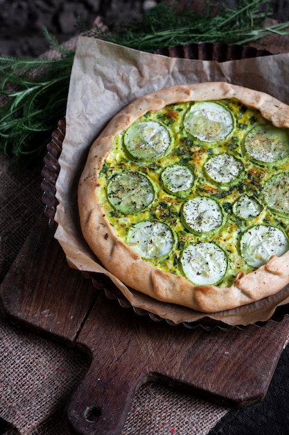 Homemade courgette and goat cheese pie on a dark rustic wooden board