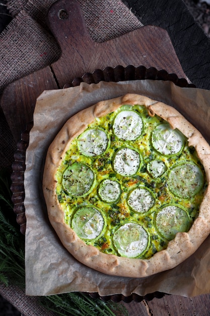 Homemade courgette and goat cheese pie on a dark rustic wooden board