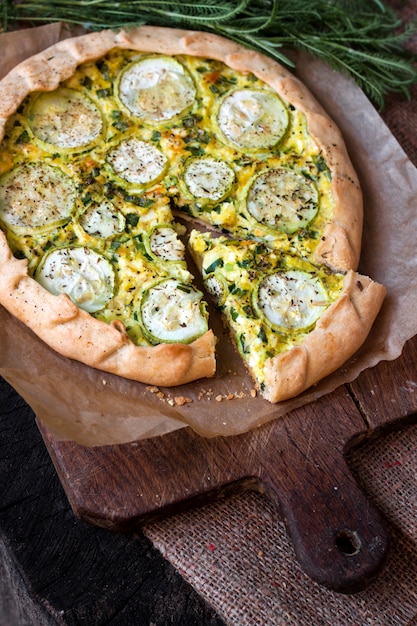 Homemade courgette and goat cheese pie on a dark rustic wooden board