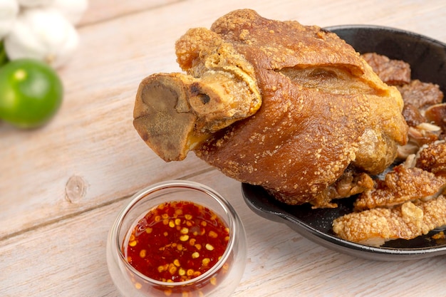 Homemade Crispy Golden Deep Fried Pork Knuckle serving in black pan on wooden table