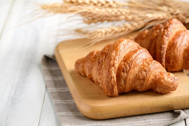 Homemade croissant on wood plate and on white wood background