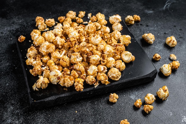 Homemade Crunchy Caramel Popcorn on marble board. Black background. Top view.