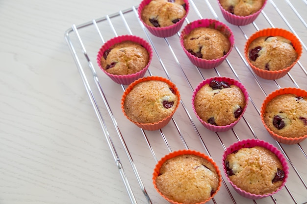 Homemade cupcakes with cherry, muffins on a wire rack on a white table