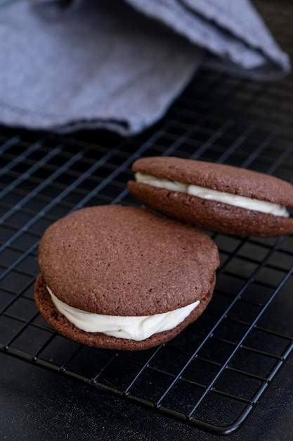 Homemade dark chocolate vegan brownie cookies with cream Dark background Selective focus