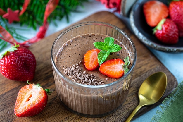 Homemade delicious chocolate mousse or panna cotta with berries on a white stone or wooden background Festive dessert