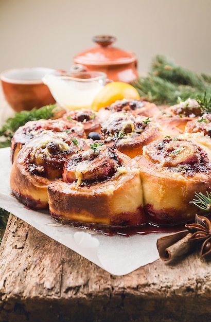 Homemade delicious cinnamon rolls with lemon and berries over wooden background