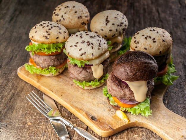 Homemade delicious grilled burgers with beef, tomatoes, cheese, sweet onions and a green salad on awood